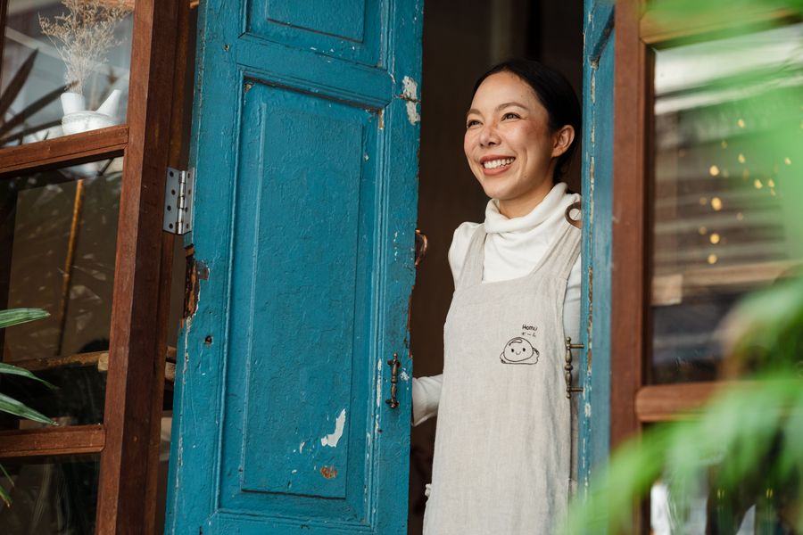Dueña de un café sonriendo en la puerta de su negocio