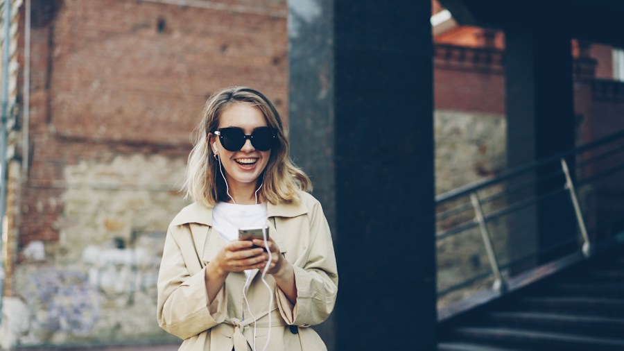 Vendedora sonriente con su celular en la calle